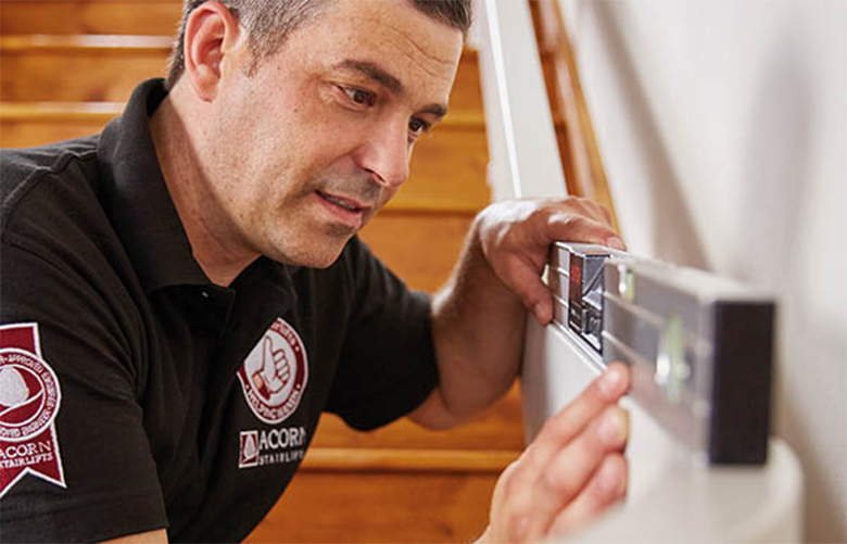 Stairlift technician measuring stairs for install