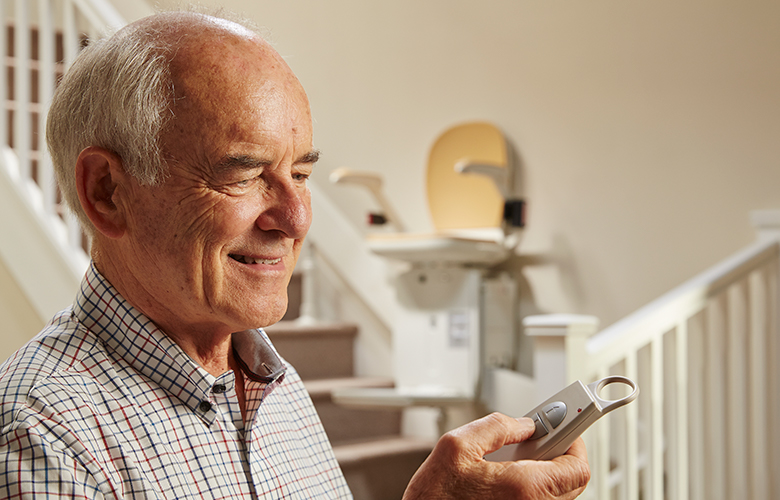 Man using remote control for stairlift to go up and down