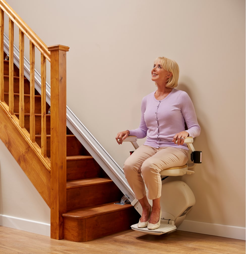 Woman at bottom of stairs on stairlift looking up